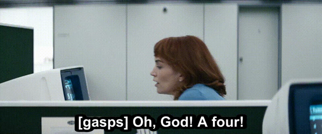 Helly R., at her desk, seen over a cubicle wall, looking at her terminal, gasping, and saying, "Oh, God! A four!"