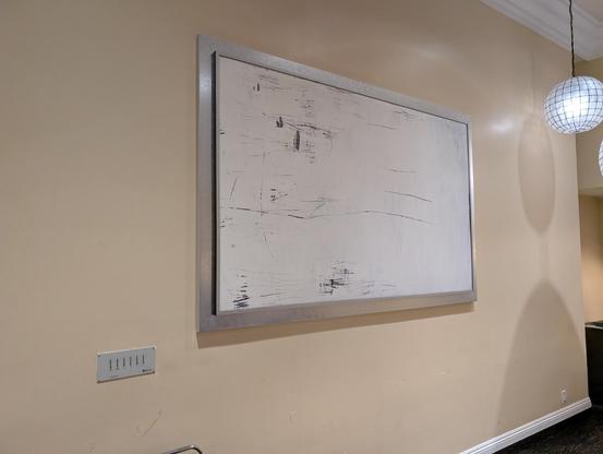 A large white rectangle hangs on the wall. It had a number of large dark scrapes and smudges.