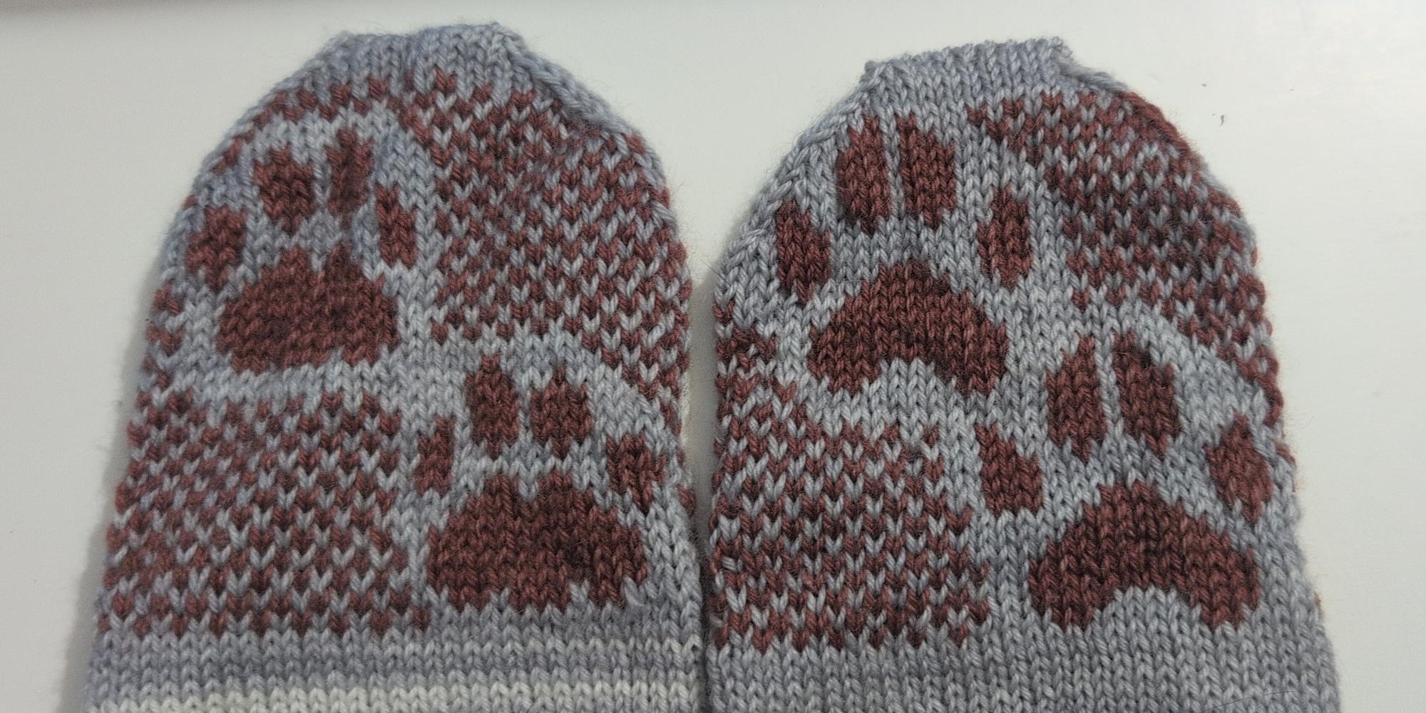The underside of the cat and dog socks showing the knitted colourwork with different shapes of paws.  (the dog ones show claws)